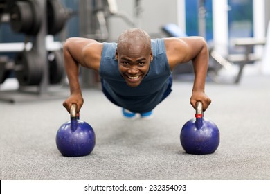 happy young african man doing push-ups exercise with kettle bells - Powered by Shutterstock