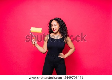 Happy young African woman with paintroller, toothy smile during home renovation