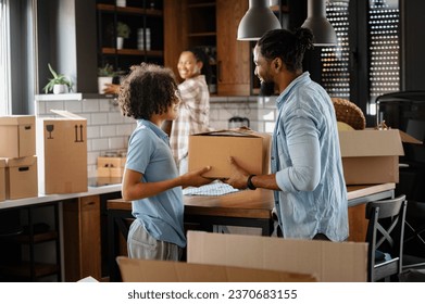 Happy young African-American family husband, wife, and teen son just moved into a new home unpacking. Relocation - Powered by Shutterstock