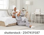 Happy young African-American mother and her daughter in pajamas sitting at home