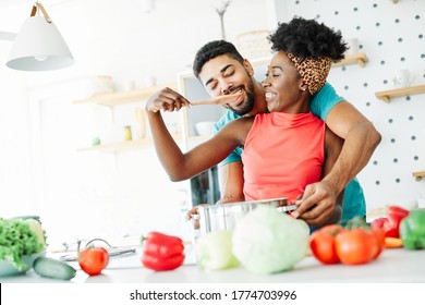 Happy young afro american couple having fun in kitchen - Powered by Shutterstock