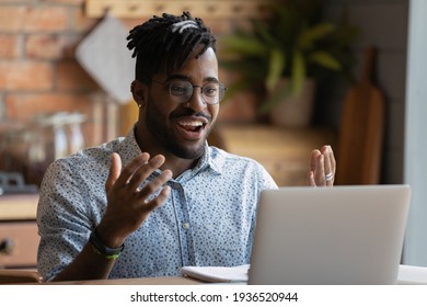 Happy young afro american man software developer run program code on pc enjoy reaching successful result. Overjoyed black guy look on laptop screen splash hands having winning hand at online blackjack