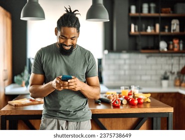 Happy young afro american man having fun preparing food and looking for recipes online using a mobile phone in kitchen, or a young businessman working from home office making connections online - Powered by Shutterstock