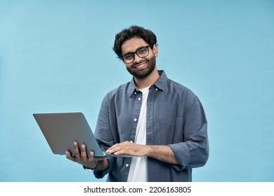 Happy Young Arab Business Man Student Or Employee Standing Isolated On Blue Background Holding Laptop Advertising Web Products For Elearning, Education Training And Webinars, Working Online.