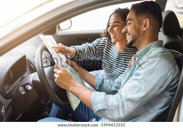 Happy\
young arab man and woman having car trip together, reading map and\
smiling, side view, copy space. Cheerful international couple\
enjoying journey by cozy auto, tracking their\
way
