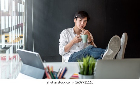 Happy young architect sitting with feet on table work in modern office.