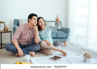 Happy Young Asian Adult Couple Looking Planning New Home At Living Room.