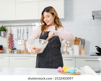 Happy young Asian beautiful female wearing apron looking at camera smiling holding bowl while kneading dough for baking cakes woman making homemade bread, dessert. Cooking concept weekends in kitchen - Powered by Shutterstock