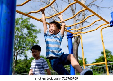 Happy Young asian boy hang the yellow bar by his hand to exercise at out door playground under the strong sunlight in summer time. - Powered by Shutterstock
