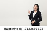 Happy young asian business woman call centre pointing finger to blank space. Welcome female operator put on smalltalk headphone standing on isolated white background.