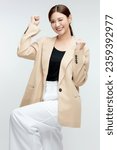 Happy young Asian business woman in blazer rejoicing, say yes, looking happy and celebrating victory, champion dance, standing over isolated white background