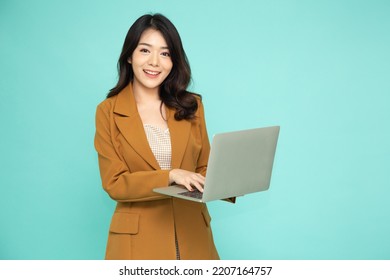 Happy young Asian business woman using laptop computer isolated on green background