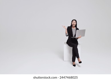 Happy young asian business woman call centre. Welcome female operator put on smalltalk headphone with laptop sitting on chair isolated on white background.