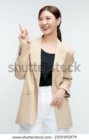 Happy young Asian business woman in blazer pointing finger up isolated on white background.