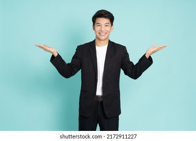 Happy young Asian businessman presenting or showing open hand palm with copy space for product isolated on green background - Powered by Shutterstock