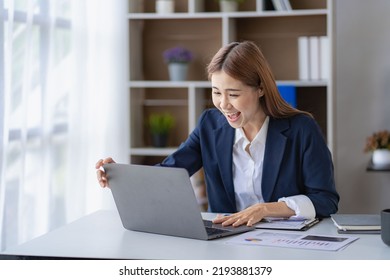 Happy Young Asian Businesswoman In A Successful Business Excitedly Raising Her Hand With A Laptop Computer In The Office. New Start Project Idea