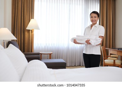 Happy Young Asian Chambermaid With A Stack Of Fresh Towels