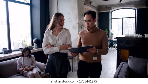 Happy Young Asian Coach Business Man And Caucasian Woman Walk Along Modern Busy Loft Office Using Tablet Slow Motion.