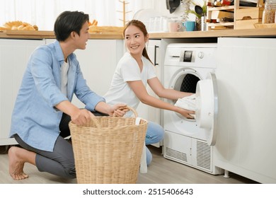 Happy young asian couple doing laundry fold clothes together using a front loading washing machine to wash laundry. Husband and wife during household routine in morning at home. - Powered by Shutterstock