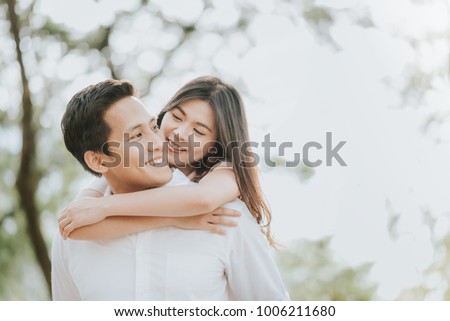 Happy young Asian couple in love having a good time and embracing in the park
