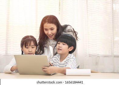 Happy Young Asian Family With Children And Their Mother Using Computer Do School Homework At Home.