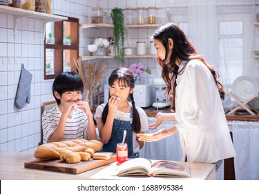 Happy Young Asian Family Have Leisure Time In Kitchen, Son And Daughter Eat Bread With Jam Mother Prepare Food, Stay At Home With Joyful Leisure Family.