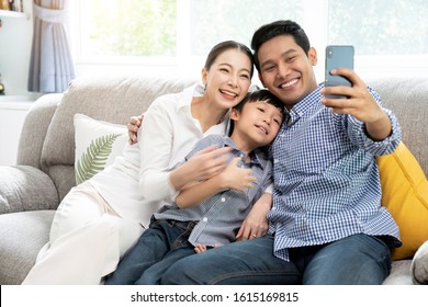 Happy Young Asian Family Taking Selfie Photo Together By Smartphone At Living Room