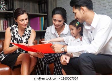 Happy Young Asian Family Talking With Psychologist Or Family Counselor In Life Insurance Coverage Or Real-estate Agent House Investment Or Bank Worker Offers Loan Or Financial Advisor With Clients.