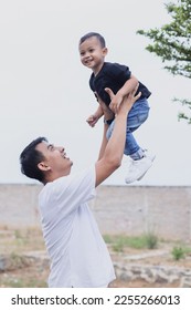 Happy young Asian father lifting up  little son in the air, spending time together outdoor.  - Shutterstock ID 2255266013