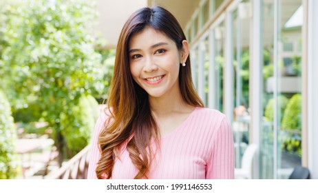 Happy young Asian female feeling happy smiling and looking to camera while relax on street in modern city. Lifestyle woman at outside house concept.