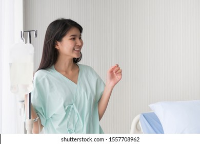 Happy young Asian female Patient is smiling while saline intravenous (IV) on hand in the hospital room. Health care and medical insurance concept. - Shutterstock ID 1557708962