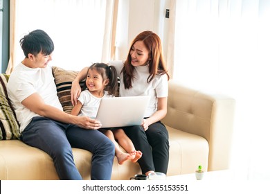 Happy young Asian girl with her lovely parents using laptop computer for education and spent quality time together. Asian family, Social Distancing, homeschooling, work from home or love concept - Powered by Shutterstock