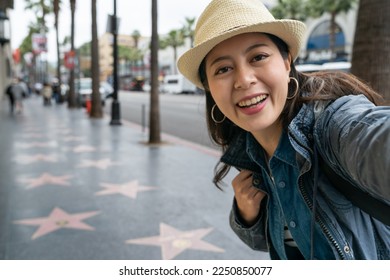 happy young Asian girl making self portrait standing outdoor on street.