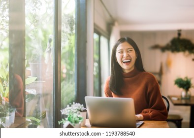 Happy Young Asian Girl Working At A Coffee Shop With A Laptop