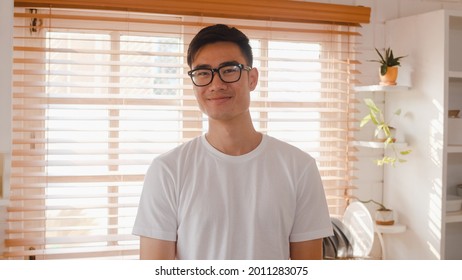 Happy young Asian male feeling happy smiling and looking to camera while relax in kitchen at home. Lifestyle man at home concept. - Powered by Shutterstock