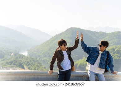 Happy young Asian man friends enjoy and fun outdoor lifestyle road trip travel on summer holiday vacation. Two generation z guy looking beautiful nature of countryside forest and mountain in sunny day - Powered by Shutterstock