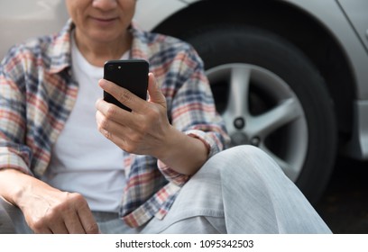 Happy Young Asian Man, Hipster Sitting On The Ground Outside A Car And Using Mobile Smart Phone, Videocalling With His Friend. Summer Holiday, Weekend Travel Concept. Close Up