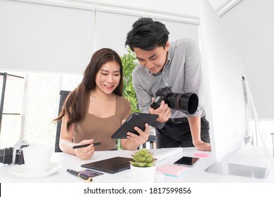 Happy Young Asian Man Professional Photographer And Woman Graphic Designer Checking A Picture On A Tablet While Working Together In The Modern Office. Business Creative People, Teamwork Concept.