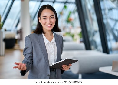 Happy young Asian saleswoman looking at camera welcoming client. Smiling woman executive manager, secretary offering professional business services holding digital tablet standing in office. Portrait - Shutterstock ID 2179380689