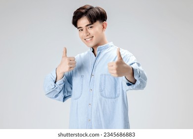 Happy young Asian smart man shows thumbs up over isolated background.  - Powered by Shutterstock