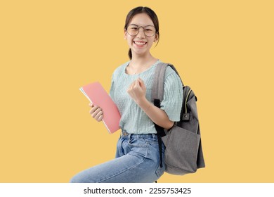 Happy Young Asian student girl standing over isolated yellow background with copy space. - Powered by Shutterstock