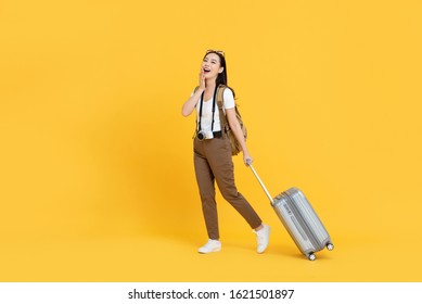 Happy Young Asian Tourist Woman With Baggage Going To Travel On Holidays Isolated On Yellow Background