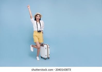 Happy Young Asian Tourist Woman Holding Baggage Going To Travel On Holidays Isolated On Blue Background.