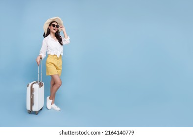 Happy young Asian tourist woman holding baggage going to travel on holidays isolated on blue background. copy space - Powered by Shutterstock