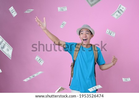 Happy Young Asian traveler man dreaming have much money, dreaming money falls from the sky, against on pink background