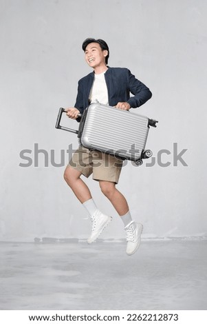 Happy Young Asian traveler man jumping with suitcase bag isolated on white background