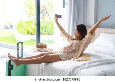 Happy Young Asian Traveler Woman Relax On Bed In Hotel Room. Travel Alone, Summer Weekend Concept.