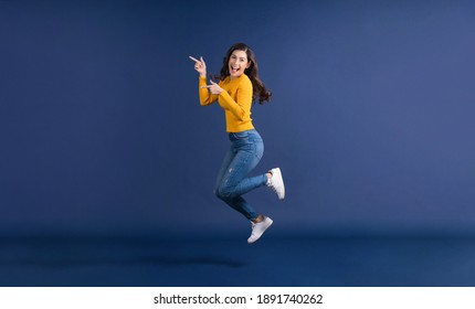 Happy Young Asian Woman In Colorful Yellow Color Casual Clothes Jumping And Presenting To Copy Space On Blue Color Background, Lifestyle And Leisure, Travel And Tourist, Travel And Vacation Concept