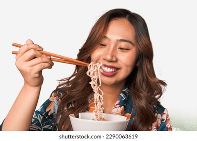 Happy young Asian woman eating noodles with chopsticks. - Powered by Shutterstock