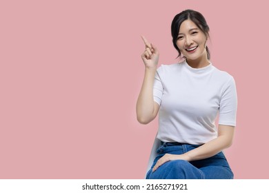 Happy young Asian woman feeling happiness and gesture pointing finger on isolated pink background with copy space. - Powered by Shutterstock